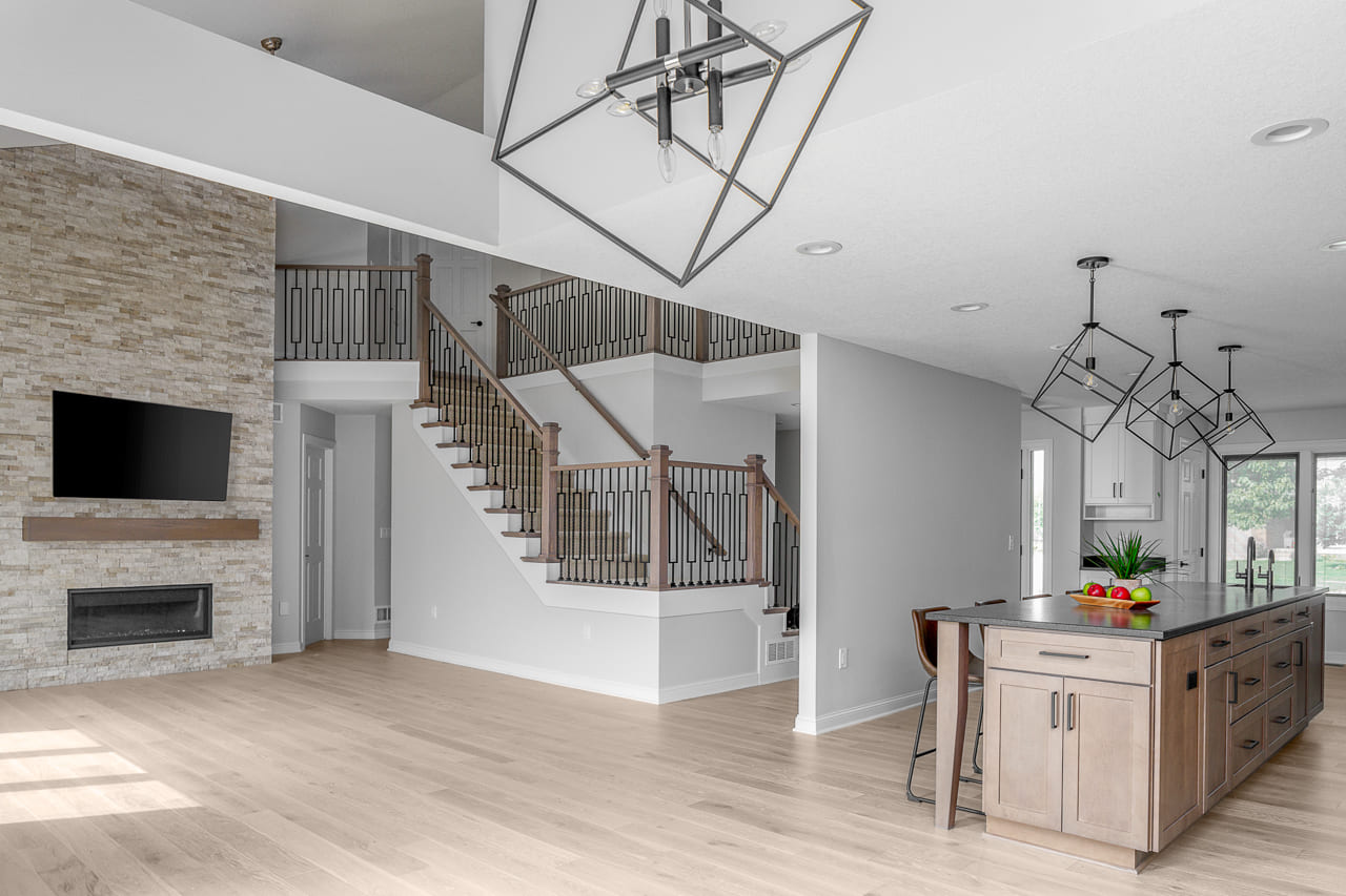 Open Concept Living and Kitchen Area with Gorgeous Stairway and Floor to Ceiling Stone Surround Fireplace