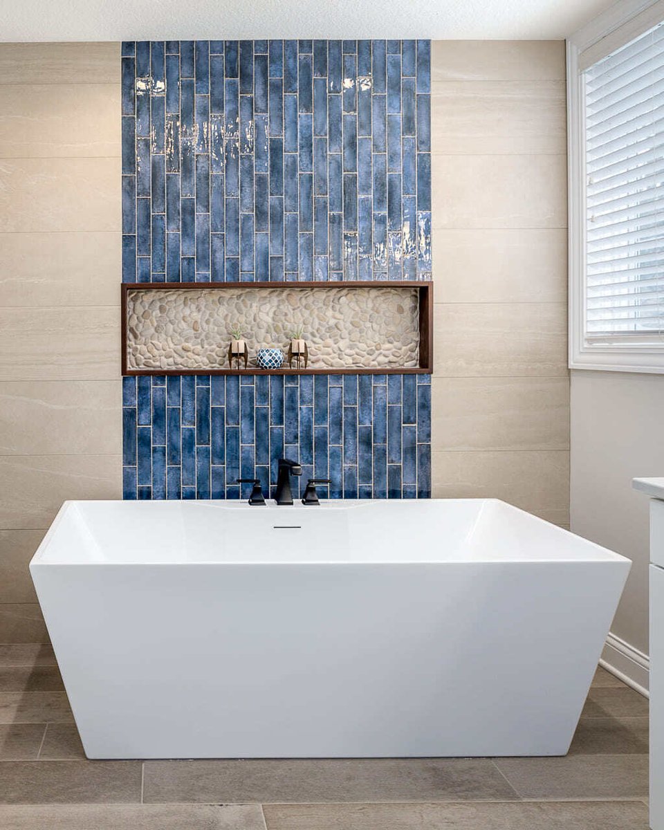 A freestanding bathtub with a shower niche above, all against a blue-tiled wall