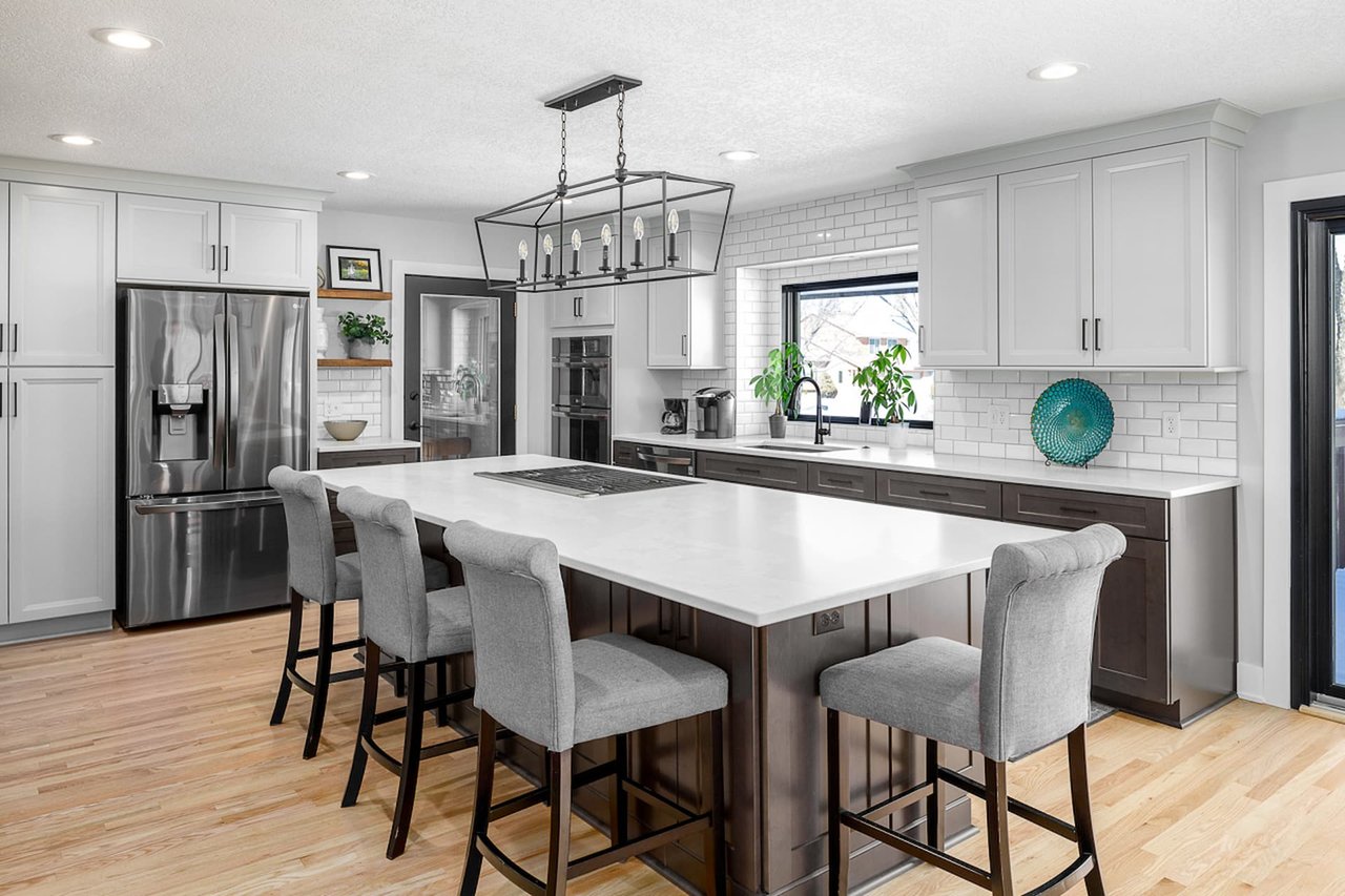 A white kitchen with brown cabinets and different types of light fixtures, including pendant lights