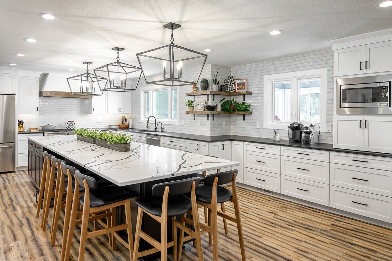 A contemporary white kitchen with ambient lighting in the form of recessed can lights and other types of light fixtures