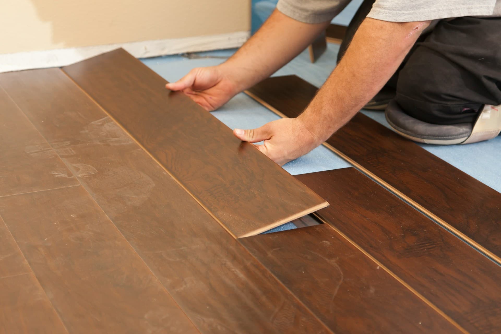 Worker laying engineered flooring in a remodeling and construction project