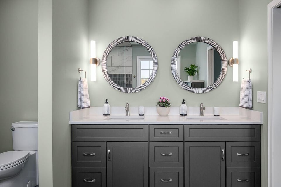 Bathroom with  sleek wall sconces and circular mirrors