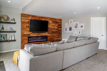 How Long Does a Basement Remodel Take in Des Moines? Modern Basement Remodel Project with Hardwood Flooring Accent Wall and Electric Built-In Fireplace | Compelling Homes