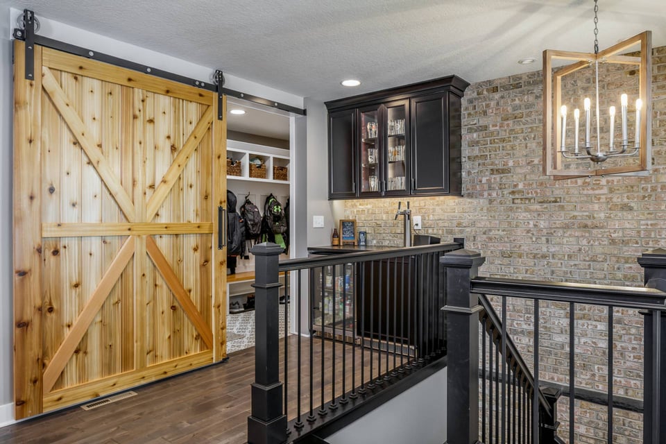 Sliding cedar door to a mudroom next to a new staircase leading to a lower