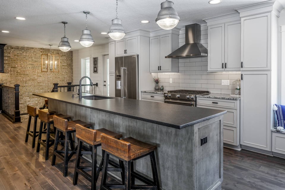 Kitchen and dining areas with galvanized pendant lights, matte stone, and more wood finishes.&nbsp;