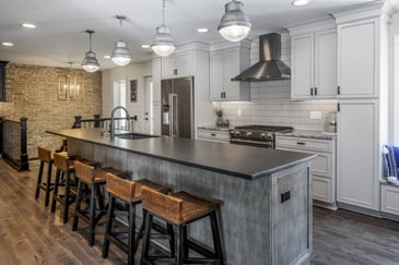 Kitchen and dining areas with galvanized pendant lights, matte stone, and more wood finishes.&nbsp;