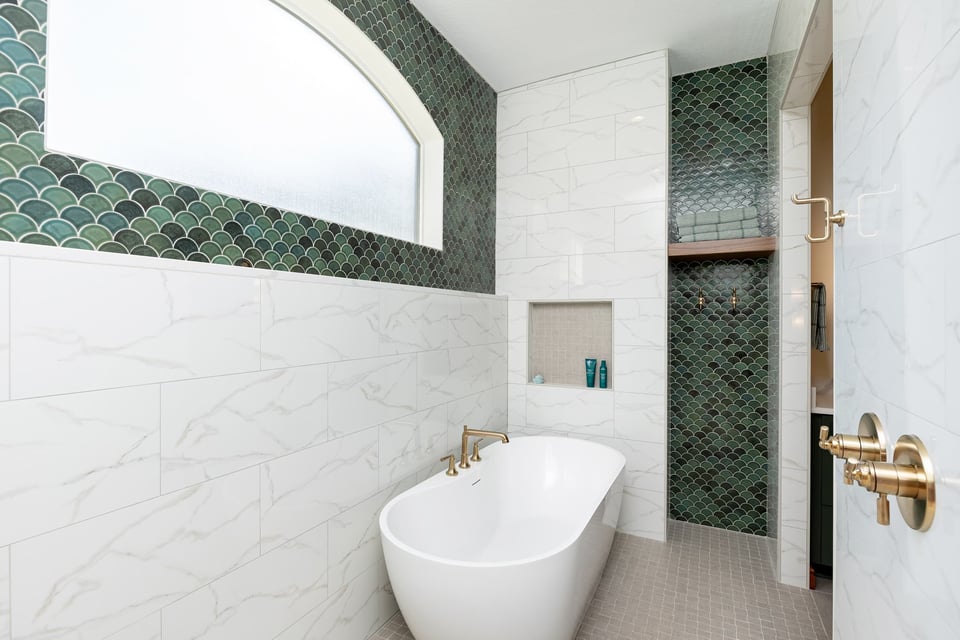 A bathtub close to a shower niche and an open shelve cabinet in a bathroom