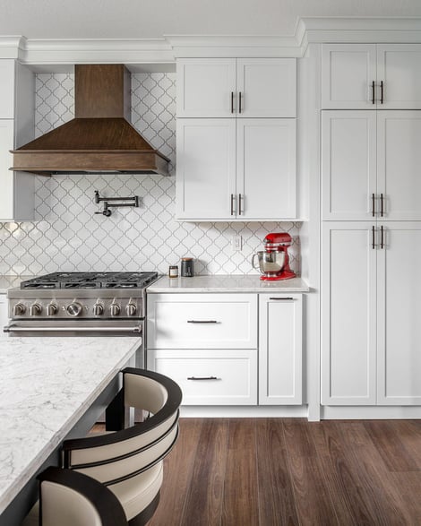 White Cabinetry with Dark Wood Fume Hood and Stainless Steel Appliances | Compelling Homes