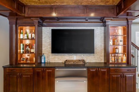 Stone Accent TV Wall Behind Custom Bar in Walk Out Basement with Lots of Natural Light | Compelling Homes Des Moines, IA