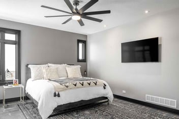 Bedroom with king sized bed and carpeted floors remodeled by Compelling Homes