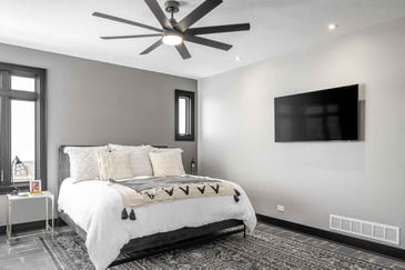 Bedroom with king sized bed and carpeted floors remodeled by Compelling Homes