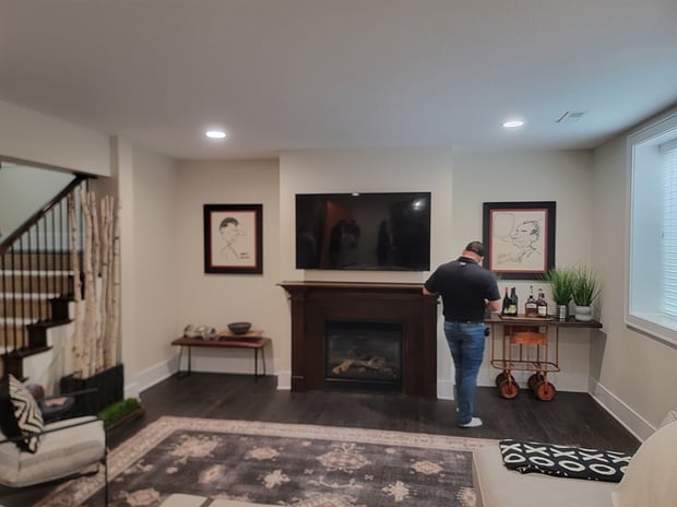 Empty basement with dark wood fireplace mantel, traditional surround, and dark hardwood floor before remodel