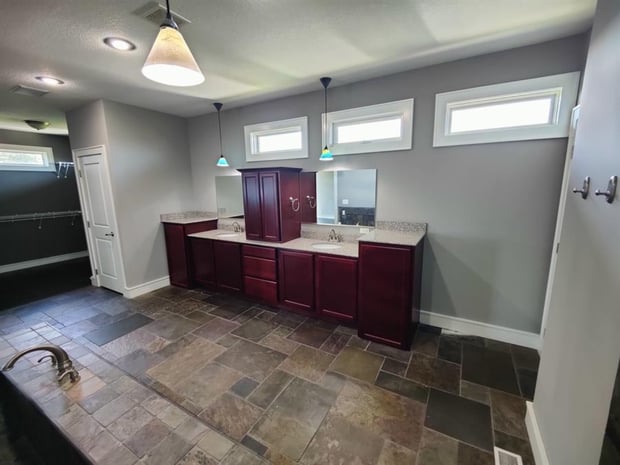 Spacious traditional bathroom with cherry double vanity, granite counters, and slate floor before remodel