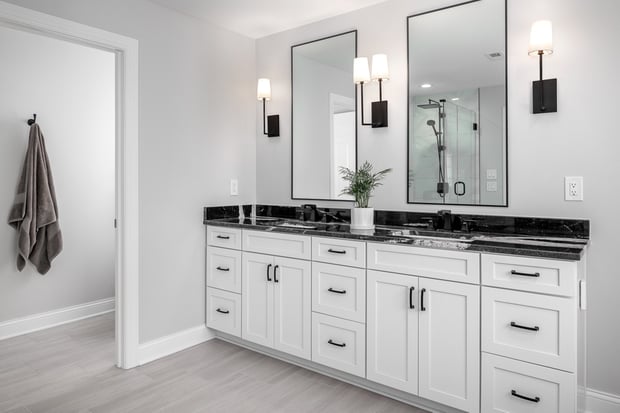 Bright modern bathroom with white shaker vanity, black granite counters, black-framed mirrors, and modern shower