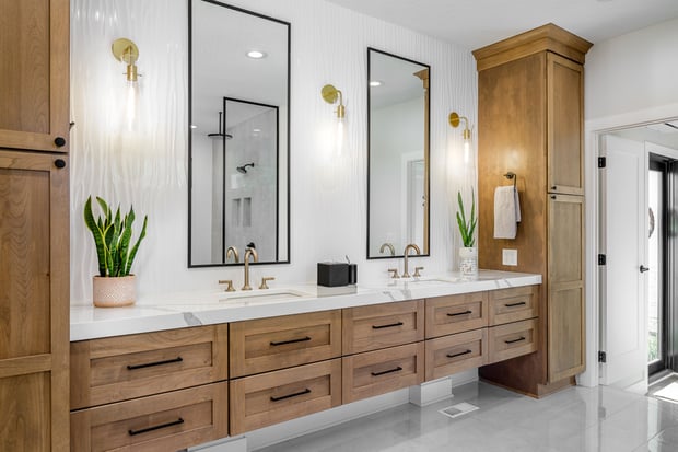 Bright modern bathroom with white wave-tile feature wall, natural wood double vanity, and brass fixtures