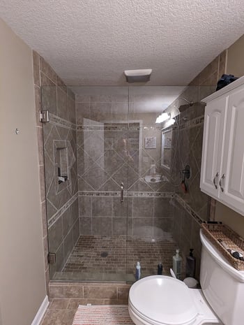Outdated hall bathroom with traditional diagonal-tile shower and dated raised-panel cabinetry before remodel