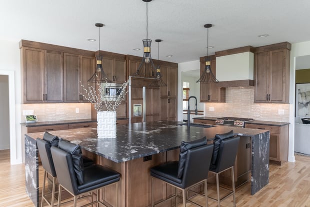 Bright modern kitchen with white shaker cabinets, marble island, geometric pendants, and black wire-back barstools