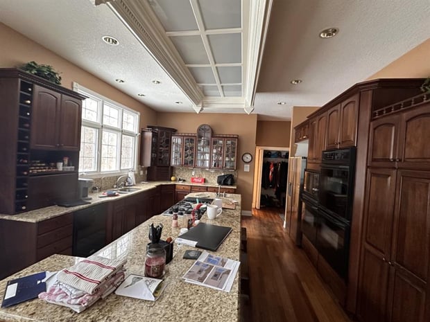 Traditional kitchen with dark cherry cabinets, beige granite counters, and coffered ceiling before remodel