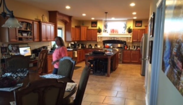 Cluttered traditional oak kitchen with dark stone counters and tile flooring before remodel