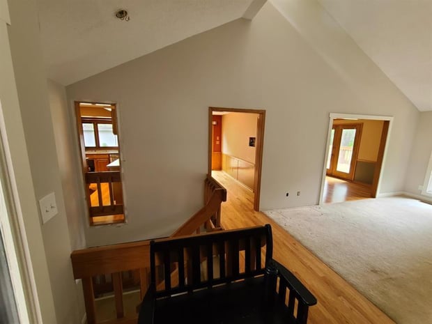 Vaulted second-floor landing with original wood trim and railings before whole-home addition and remodel