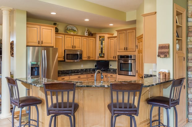 Traditional maple kitchen with dark green granite peninsula, fluorescent box lighting, and original hardwood floors