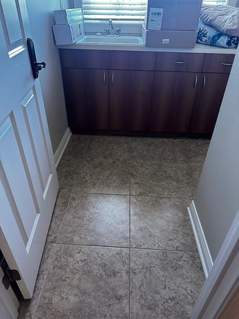 Outdated utility space with dark cabinets, dated tile floor, and basic stainless sink before remodel