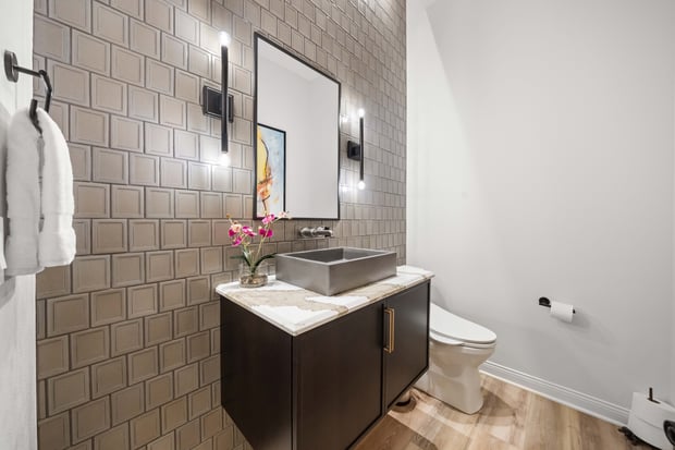 Modern powder room with gray brick-tile feature wall, dark floating vanity, vessel sink, and modern art