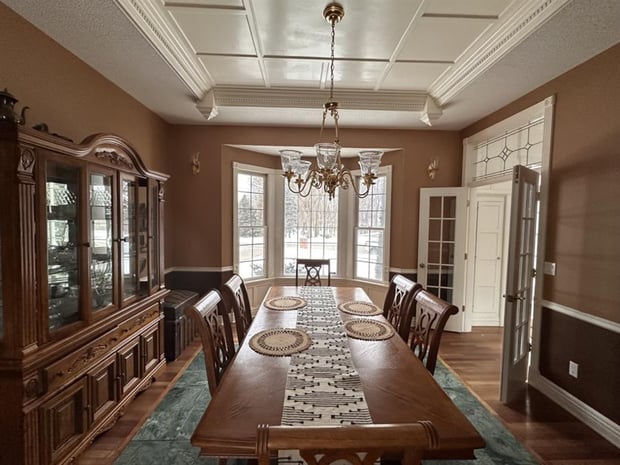 Traditional dining room with wood china cabinet, coffered ceiling, brass chandelier, and brown walls before remodel