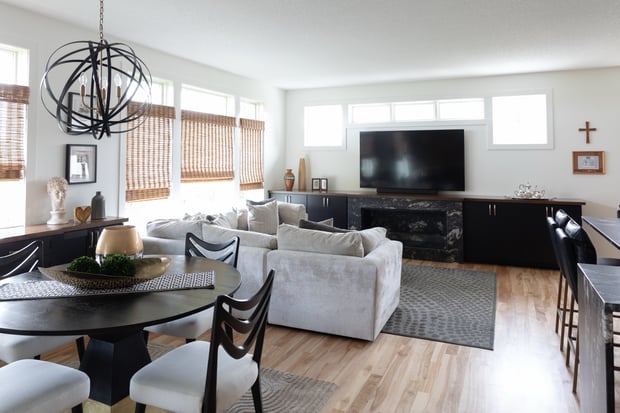 Modern living room with sphere chandelier, dark fireplace surround, gray sectional, and black storage cabinets