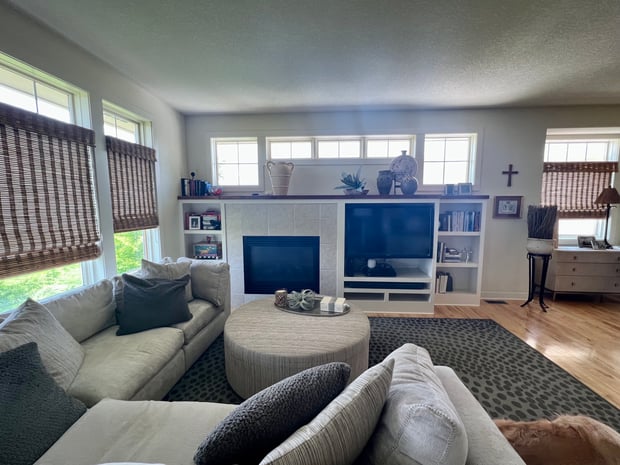 Traditional living room with white tile fireplace surround, basic built-ins, and beige sofas before remodel