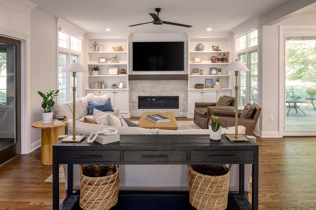 Modern living room with stacked stone fireplace, white built-ins, mounted TV, and neutral sectional