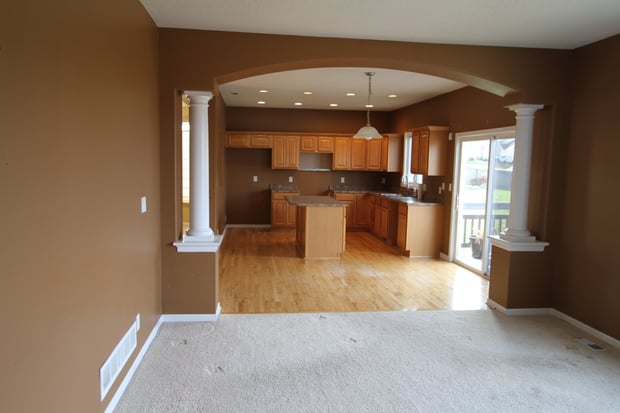 Traditional main floor with dark walls, classical columns, oak kitchen cabinets, and dated finishes before remodel