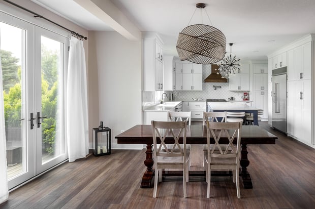 Open dining and kitchen with sphere chandelier, sputnik fixture, white shaker cabinets, and farmhouse table
