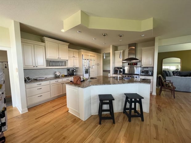 Closed-off traditional kitchen with cream cabinets, dark granite peninsula, and soffit ceiling before remodel