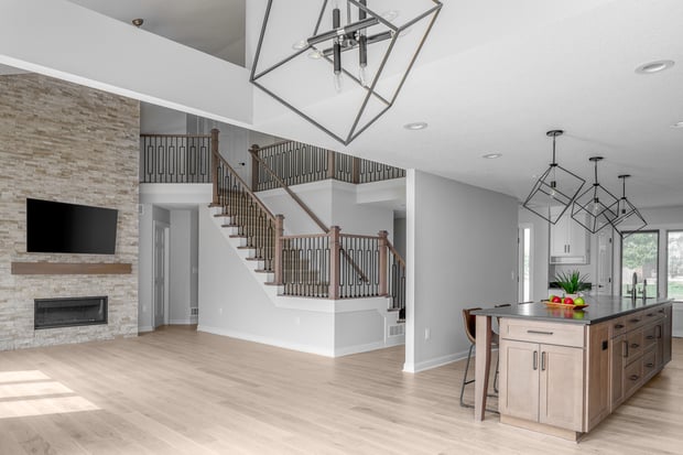 Modern open-concept main floor with stone fireplace, geometric pendants, and updated wood-and-iron staircase