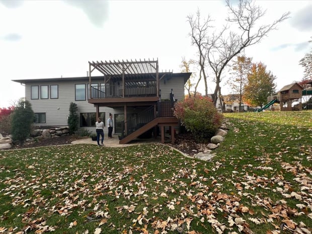 Exterior view of two-story home with raised deck and suburban backyard before addition