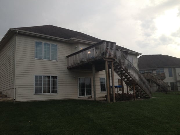 Exterior of beige two-story house with raised wood deck before addition