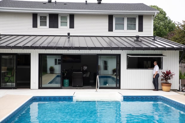 Indoor-outdoor pool addition with metal-roofed pavilion, sliding glass doors, and integrated patio space