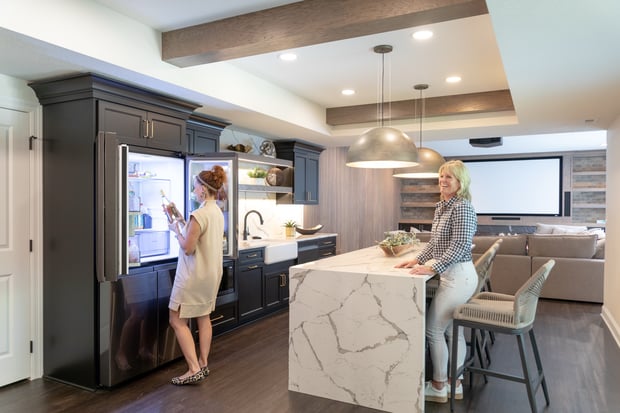 Updated basement entertaining space with marble waterfall island, custom cabinetry, and projection screen