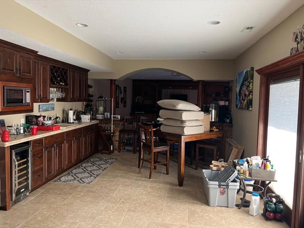 Cluttered traditional basement bar with cherry cabinets, granite counter, and dated decor before remodel