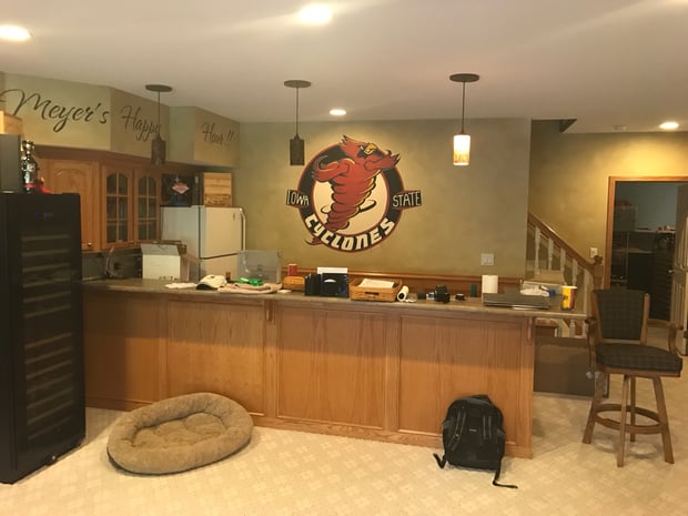 Traditional basement bar with cherry cabinets, sports decor, and themed wall lettering before remodel