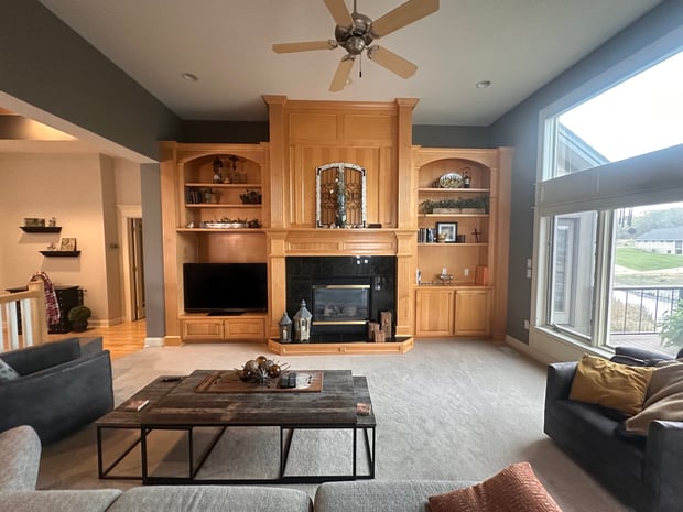 Traditional living room with light oak built-ins flanking dated gas fireplace and ceiling fan before remodel