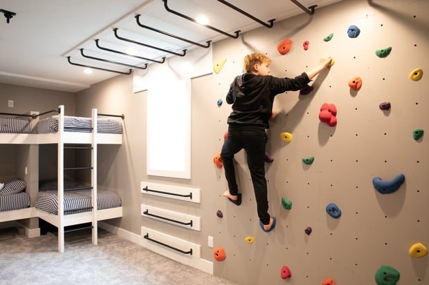 Custom kids workout room with climbing wall, monkey bars, and built-in bunk beds