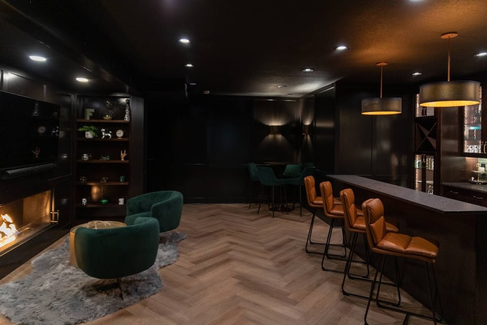 Moody basement with bar stools, pendant lights and drinking area near a fireplace