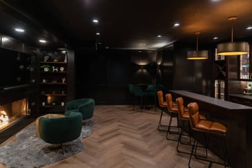 Moody basement with bar stools, pendant lights and drinking area near a fireplace
