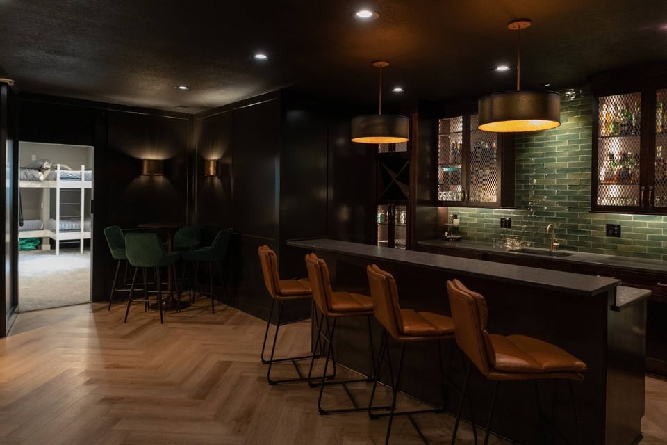 Basement Bar with Stools, Counter and Pendant Lights and Drinks on Shelves
