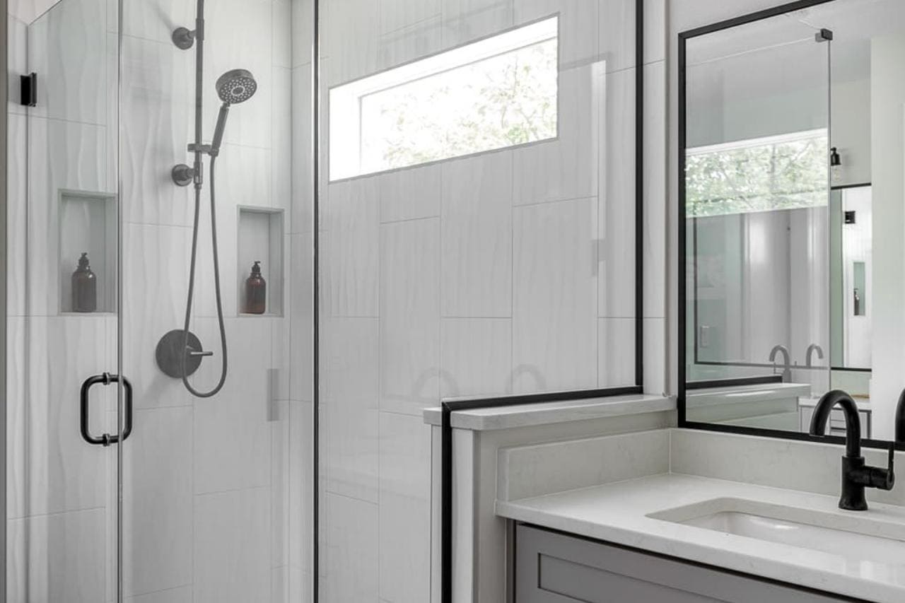 Bathroom Remodel with Glass Walk In Shower and Natural Light with Minimalistic Grey Vanity and Matte Black Hardware | Compelling Homes