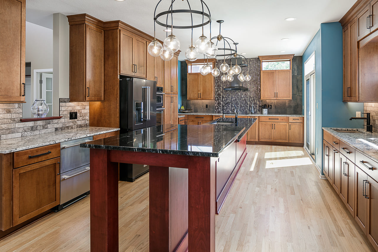 Bold and colorful kitchen featuring industrial lighting and hidden door in cabinets