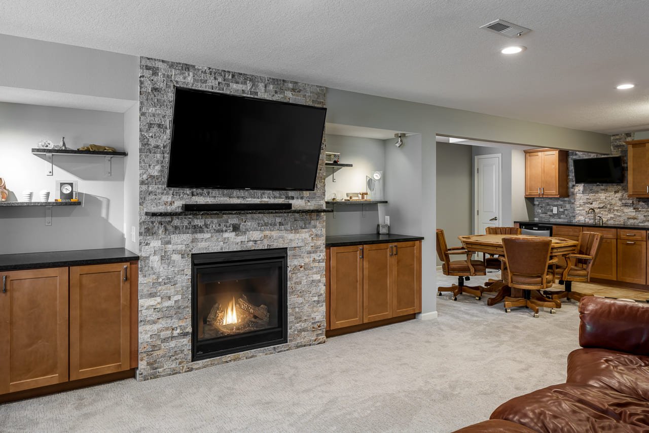Basement remodel featuring stone fireplace and surrounding built-ins